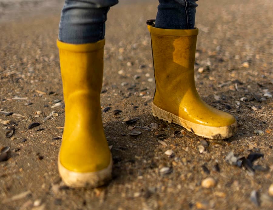 Gele regenlaarsjes op het schelpenstrand van Westende