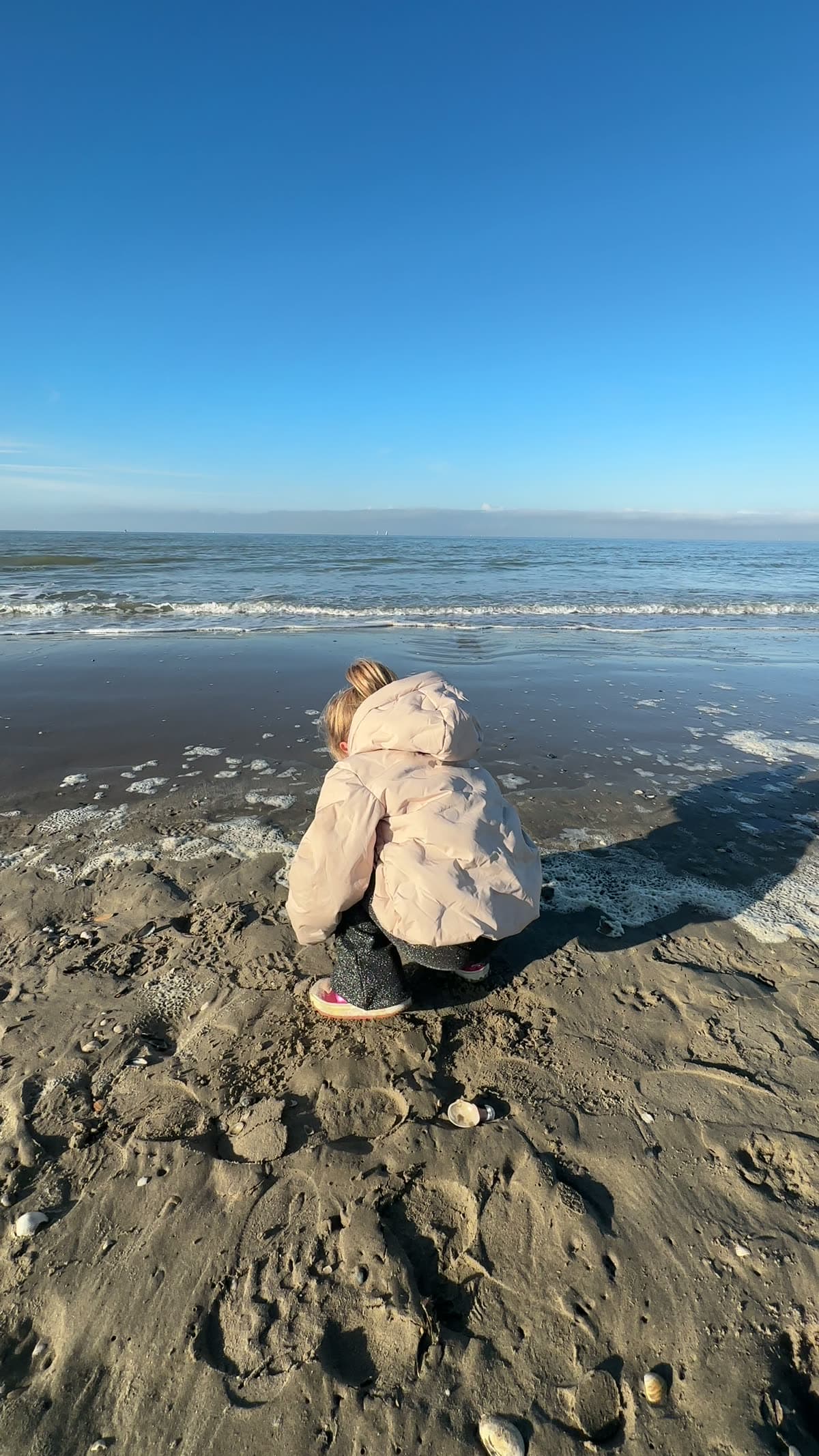 Meisje zoekt schelpjes aan de waterlijn op het strand van Westende in de herfst